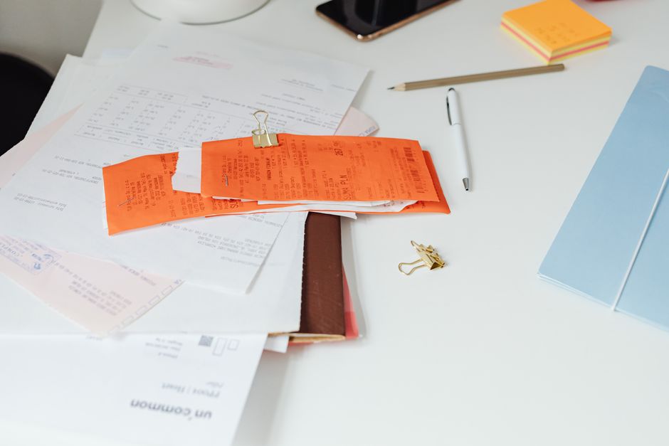 Receipts held with a clip on a white desk among papers and a pen