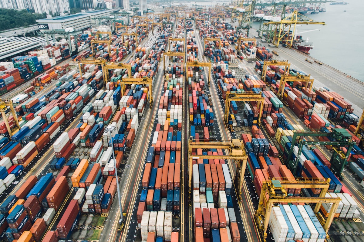 Shipping containers stacked in rows at a port terminal, seen from above