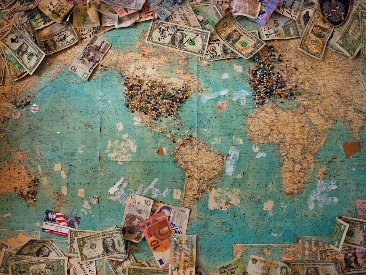 A world map covered in map pins and banknotes from many countries