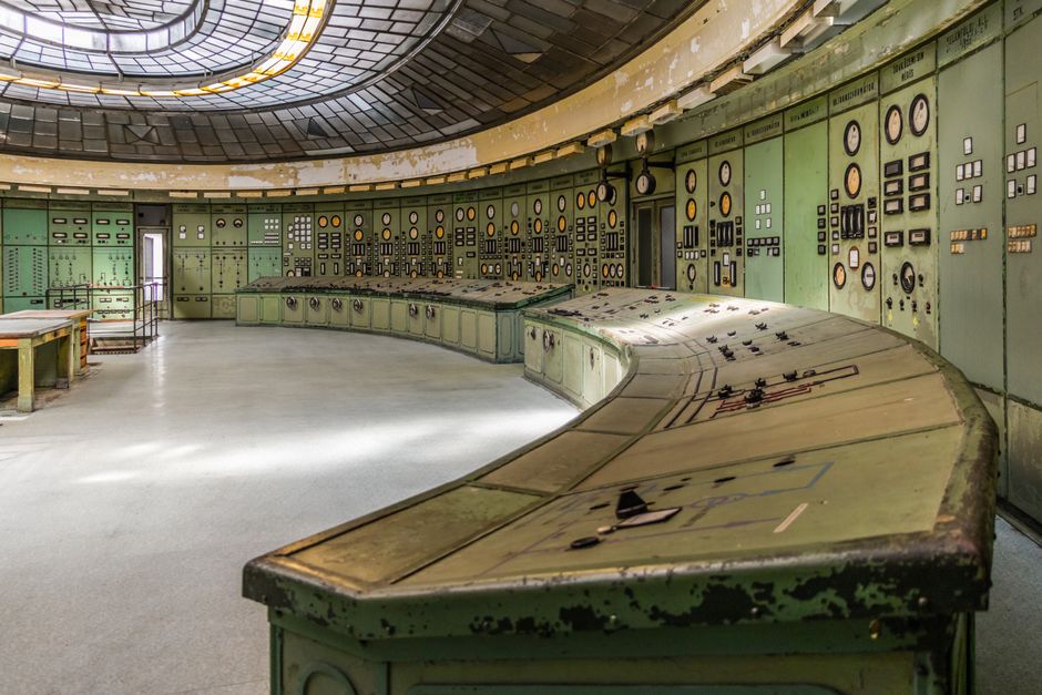 A disused power station control room, curved desks and banks of dials